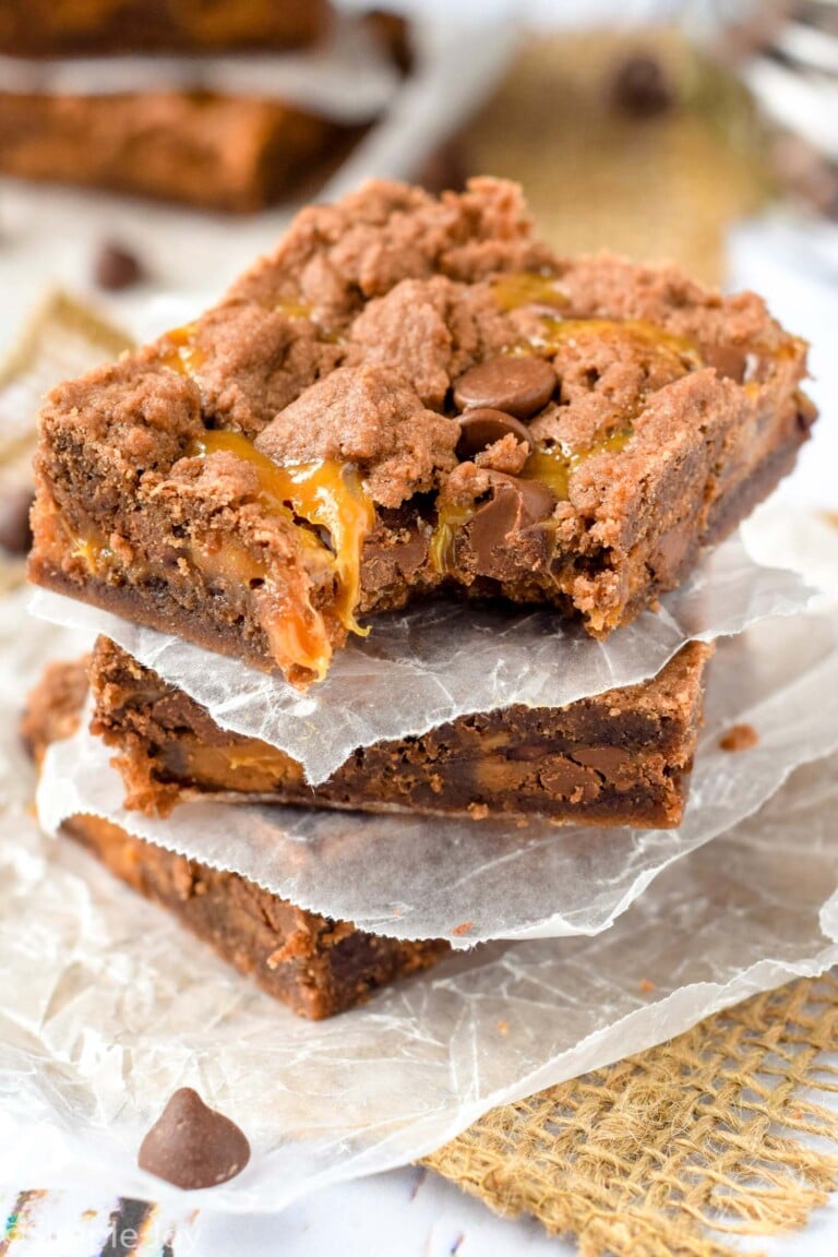 Caramel Brownies cut and stacked with wax paper separating.