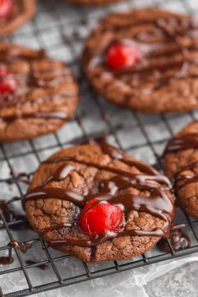 close up of a chocolate covered cherry cookie on a wire rack to cool