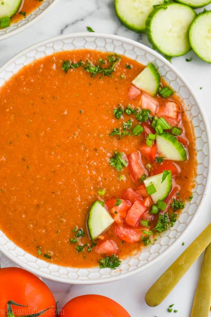 overhead view of a white bowl filled with gazpacho recipe and garnished with chopped fresh vegetables