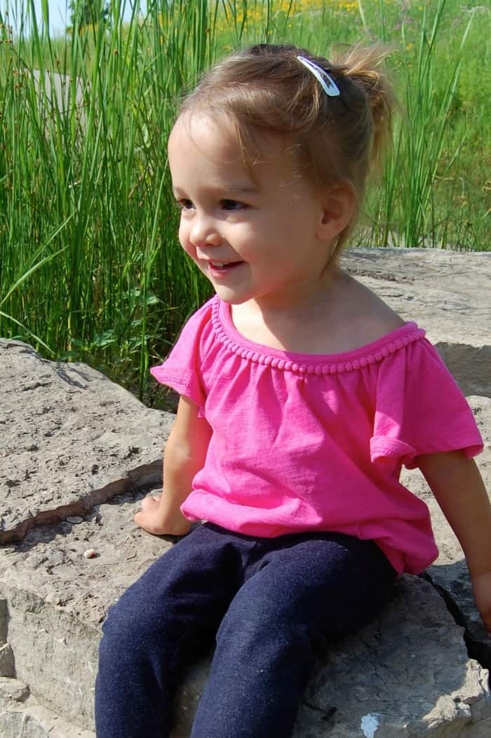 Picture of toddler girl in a pink top and blue pants. 