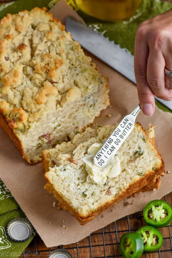 spreading butter on a piece of jalapeno popper beer bread