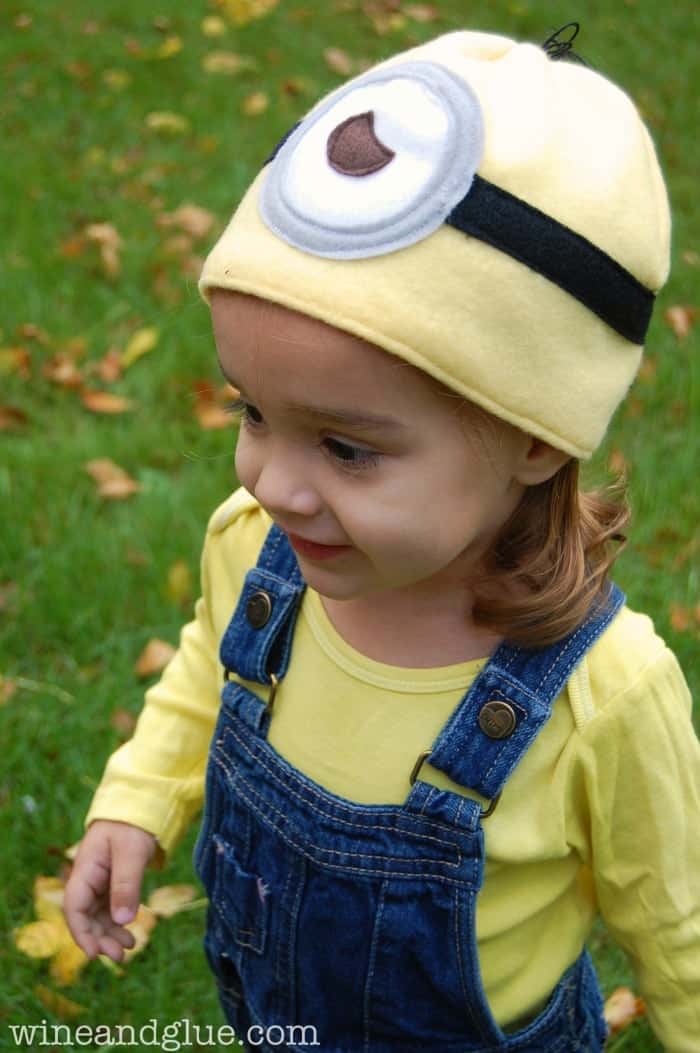 little girl in yellow shirt and overalls with a minion hat