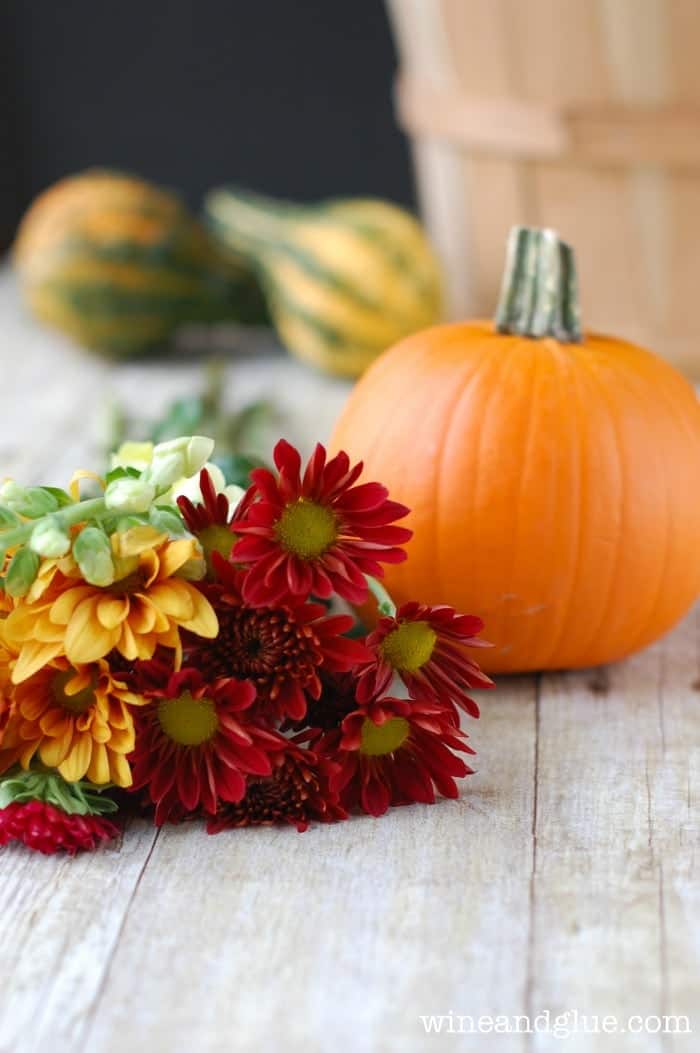 bunch of flowers with a small pumpkin sitting next to it