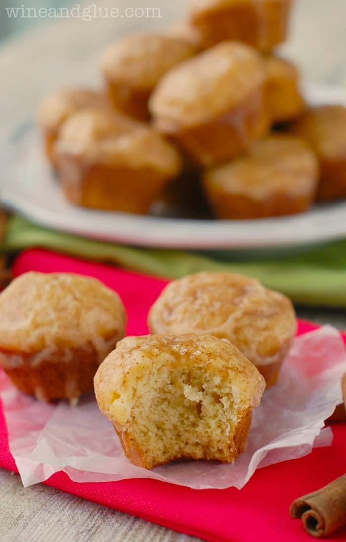 a group of three eggnog muffins with a bite missing off the front one and a plate of more in the background