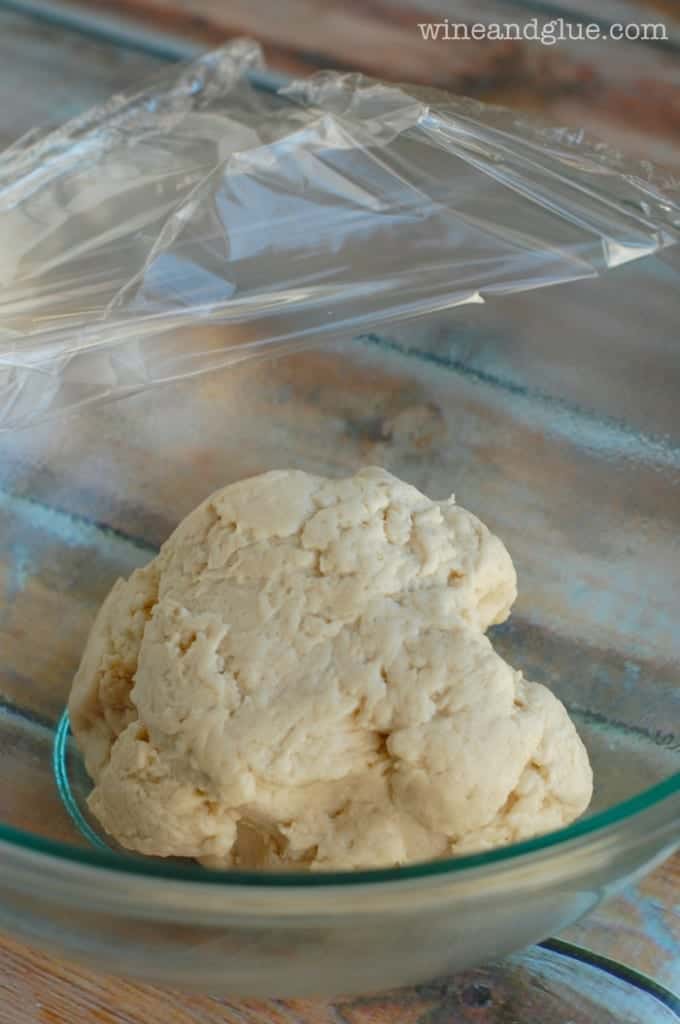 a large glass bowl with homemade pizza dough before it has risen