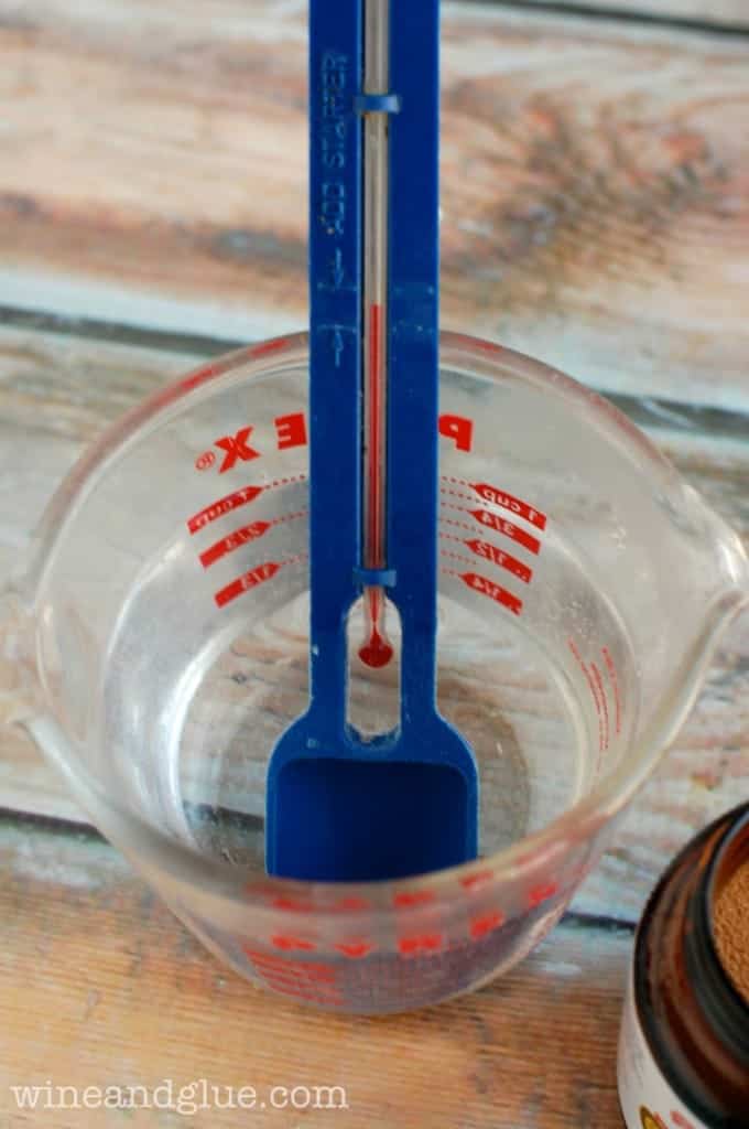 a glass measuring cup with a thermometer to get the correct temperature of water