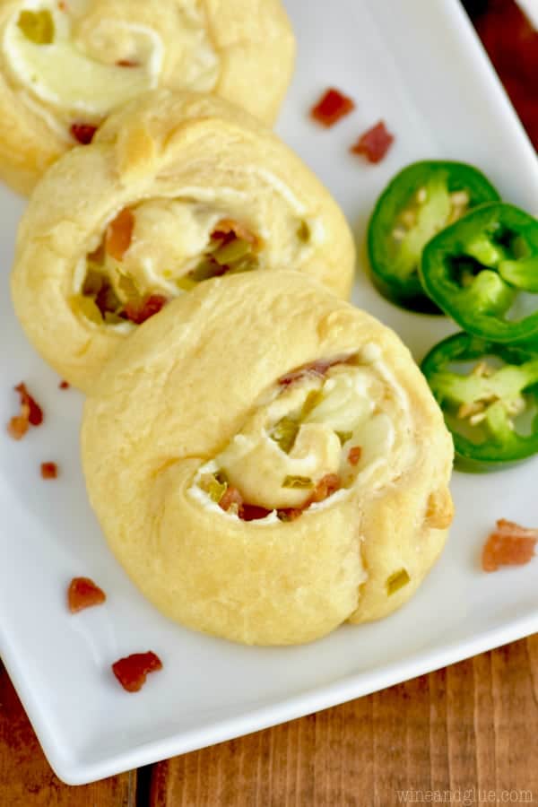 three jalapeño popper pinwheels (made with cream cheese and crescent roll dough) on a white rectangular plate