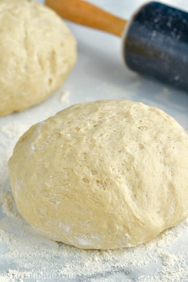 a picture of a ball of dough on a marble counter top with a rolling pin the background