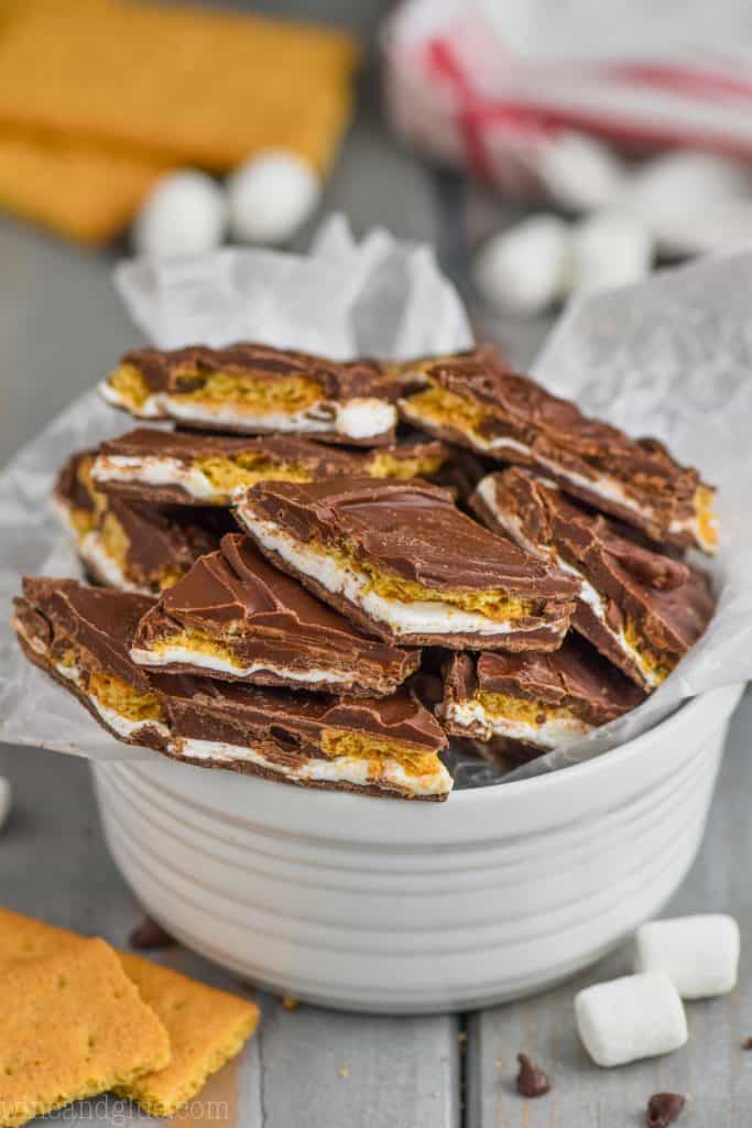small white bowl filled with pieces of chocolate s'mores bark that has graham crackers and marshmallow fluff in it