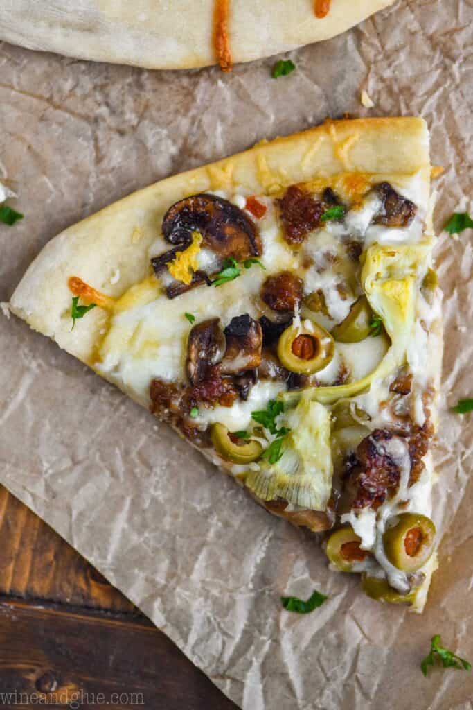 a single piece of white pizza sitting on a piece of parchment paper, garnished with parsley