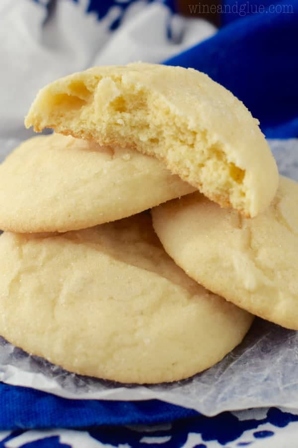 a sugar cookie that has been broken in half on top of a pile of three other sugar cookies