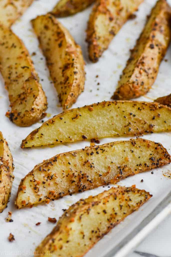 baked potato wedges that have been seasoned and are on a baking sheet