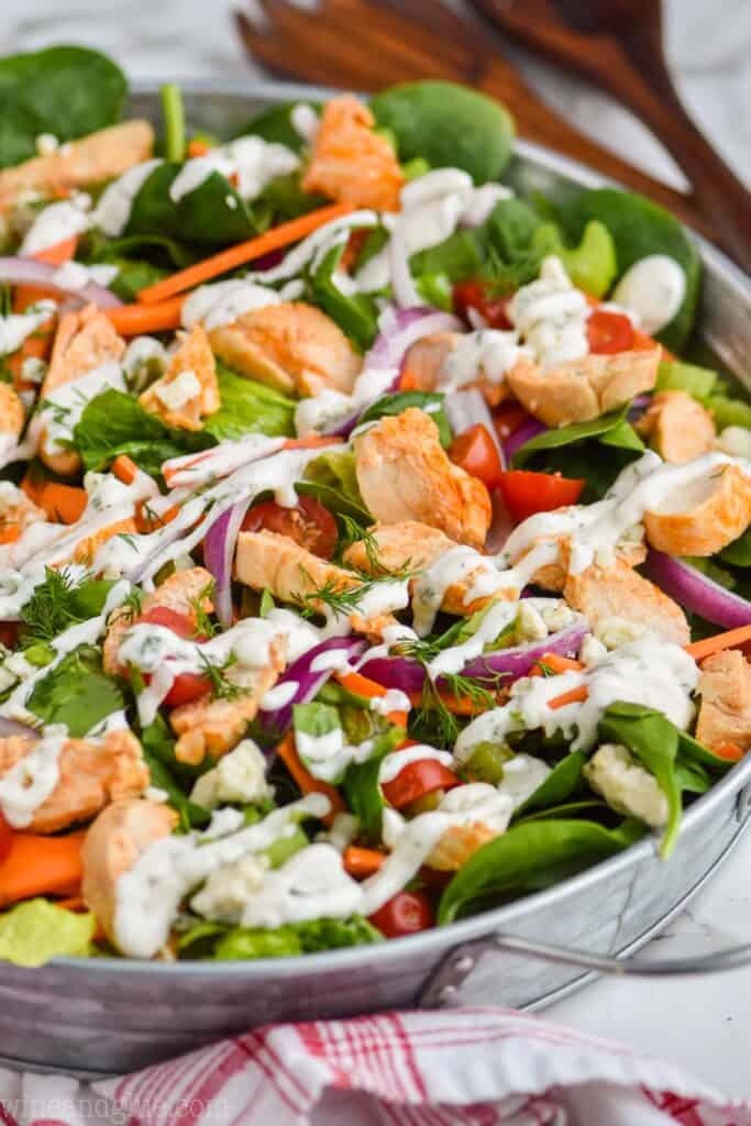 side view of a buffalo chicken salad in a galvanized metal try, dressed with homemade ranch dressing and full of fresh vegetables