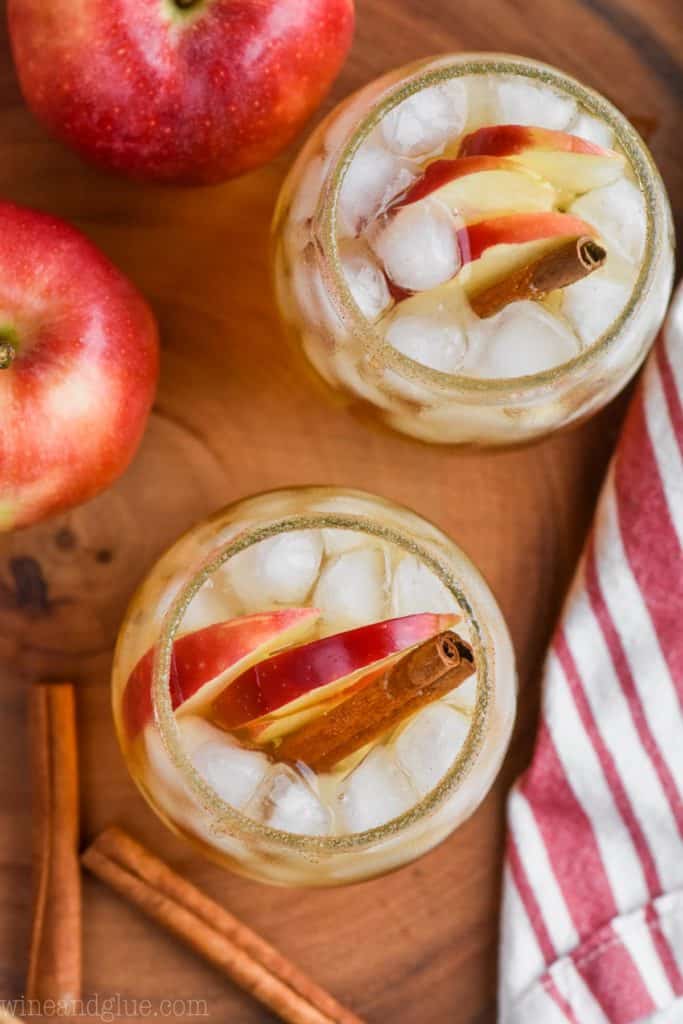 overhead view of two glasses of hard cider and tequila recipe in glasses with apples and cinnamon sticks