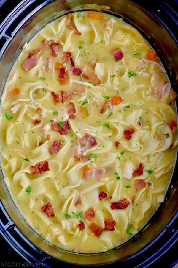 overhead view of a slow cooker full of chicken noodle soup with bacon and ranch seasoning