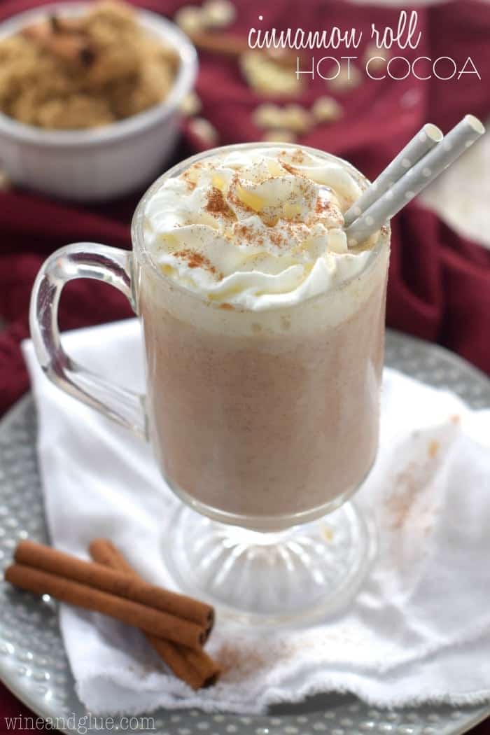 A mug of the Cinnamon Roll Hot Cocoa topped with whipped cream and ground up cinnamon. 