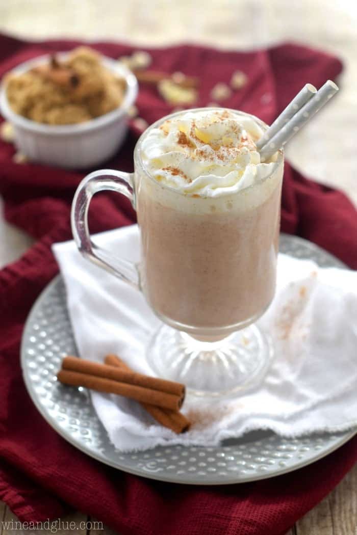 A mug of the Cinnamon Roll Hot Cocoa topped with whipped cream and ground up cinnamon. 