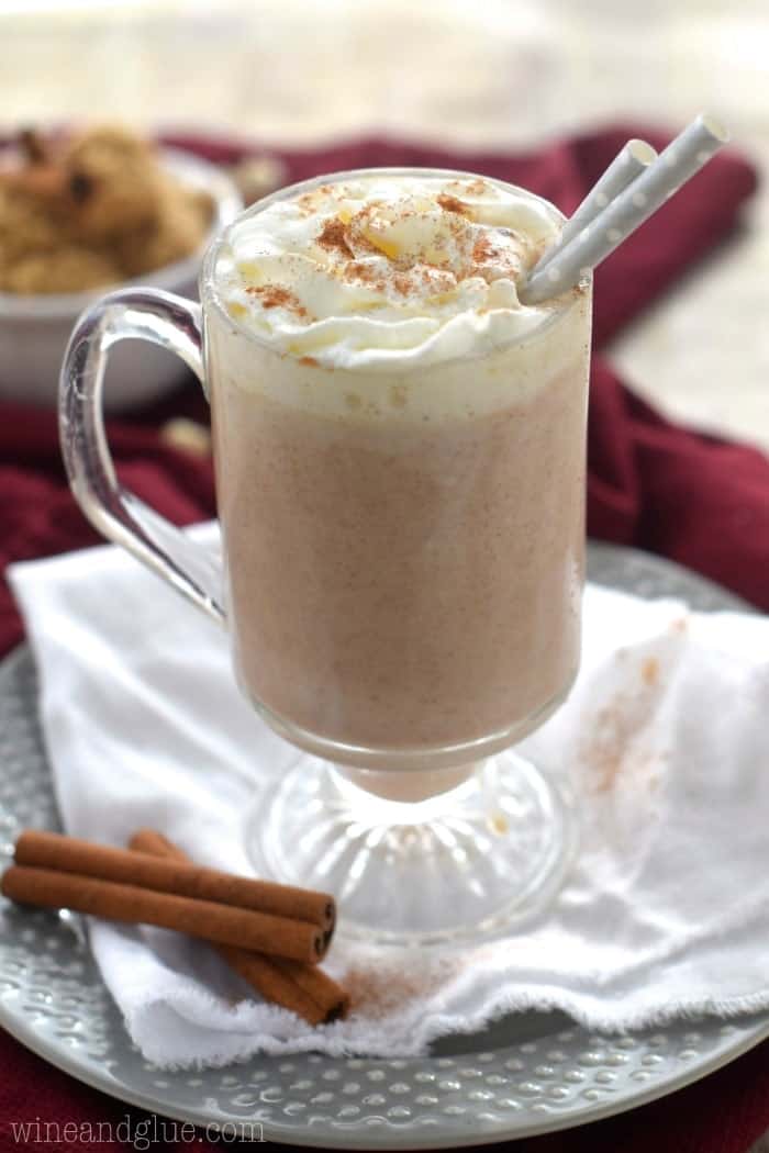 A mug of the Cinnamon Roll Hot Cocoa topped with whipped cream and ground up cinnamon. 