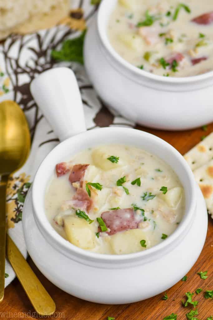 small white soup bowl full of new england clam chowder recipe and garnished with parsley