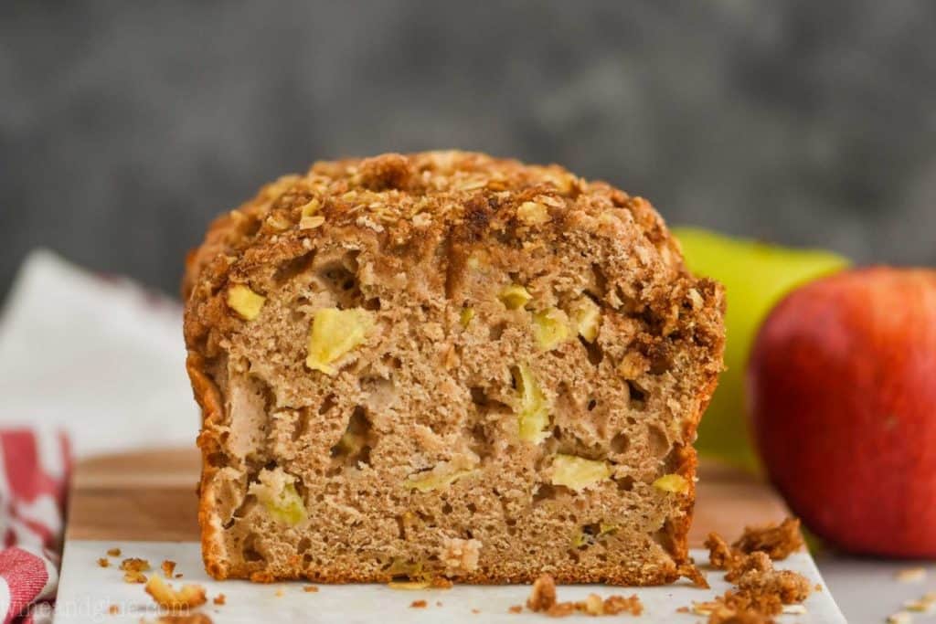 landscape photo of a cross section of apple cinnamon bread with apples in the background