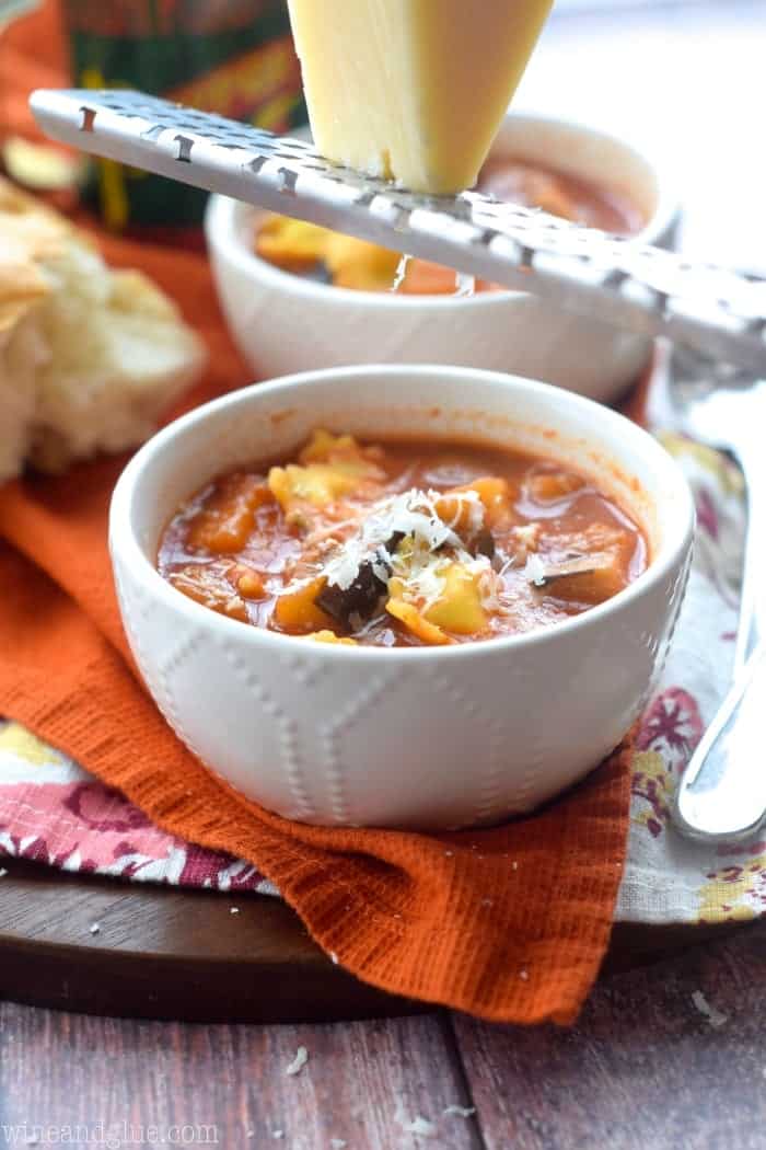 two bowls of ravioli soup with parmesan grated into it