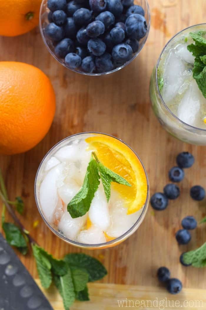 overhead photo of two glasses with orange blueberry mojitos