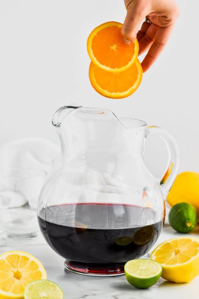 oranges being added to red wine to make red wine sangria