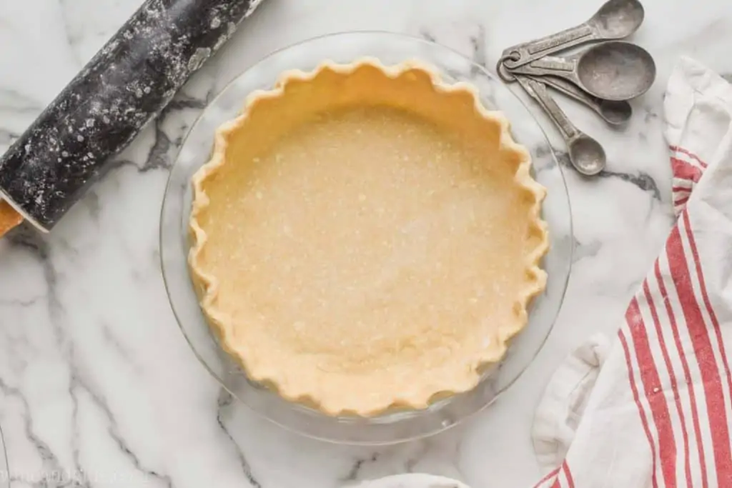 a pie crust recipe that has been transferred to a glass pie pan and the rim of it has been pinched