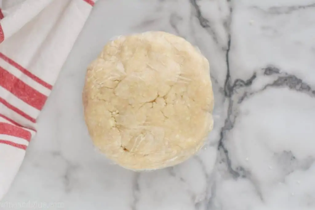 a disk of pie crust that has been wrapped tightly with plastic wrap to be put in the refrigerator