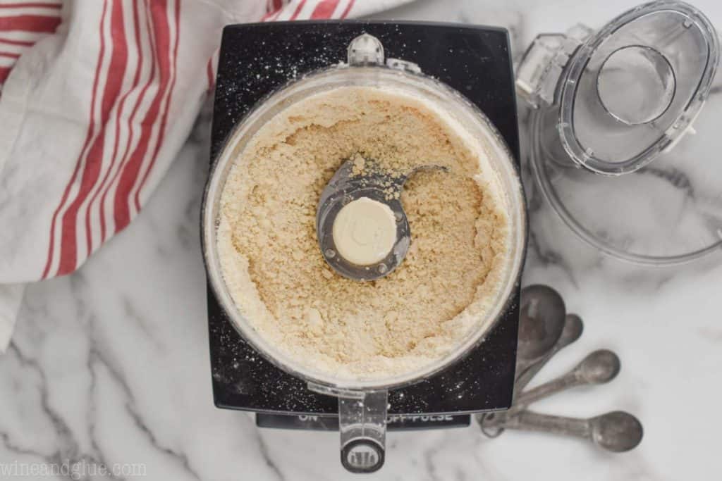 overhead of a food processor that has had cold butter and shortening added and now the last 1/2 cup of flour is blended in to make  fine crumb mixture