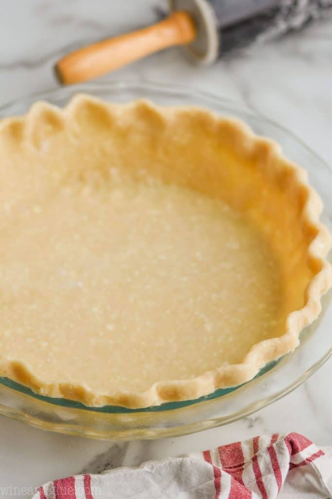 a pie crust recipe that has been rolled out, edges pinched, and placed in a clear pie pan