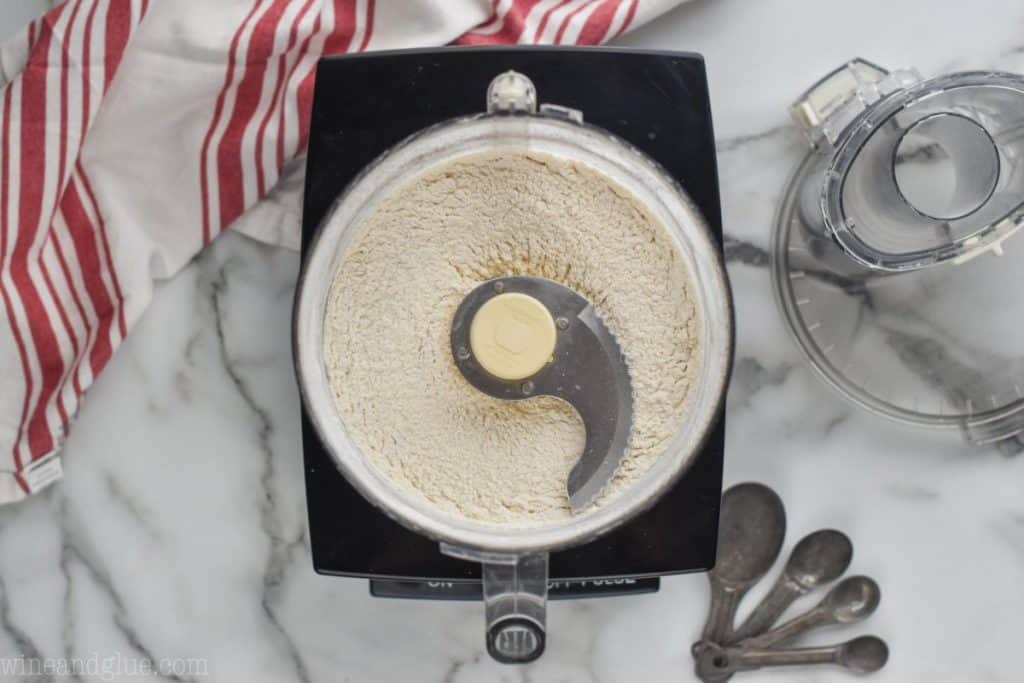 overhead view of a food processor with flour, sugar, and salt blended together to create an easy pie crust