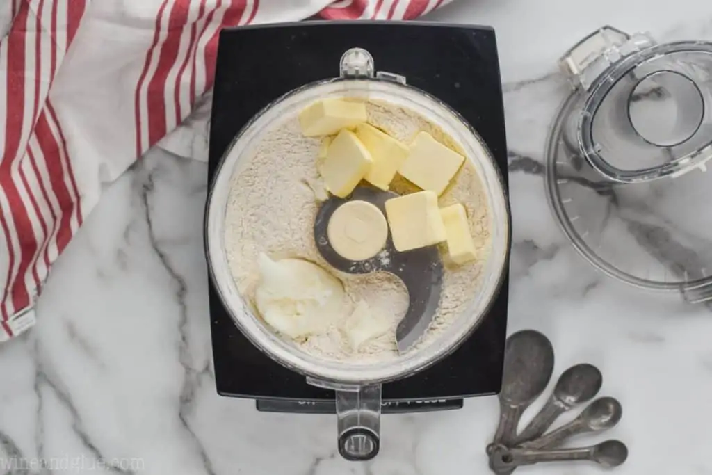 overhead of a food processor where cold butter and shortening have been added to a flour mixture