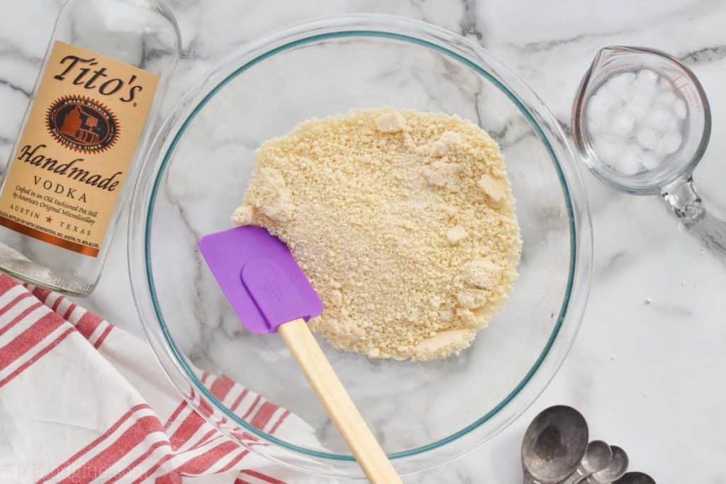 overhead view of a pie crust recipe in a bowl before vodka and water are added