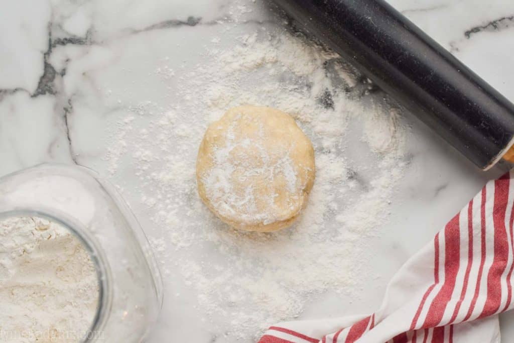 a disc of pie dough that has been refrigerated and is ready to be rolled out on a very well floured surface