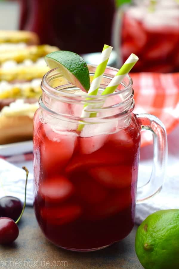 a glass of cherry limeade garnished with a lime wedge