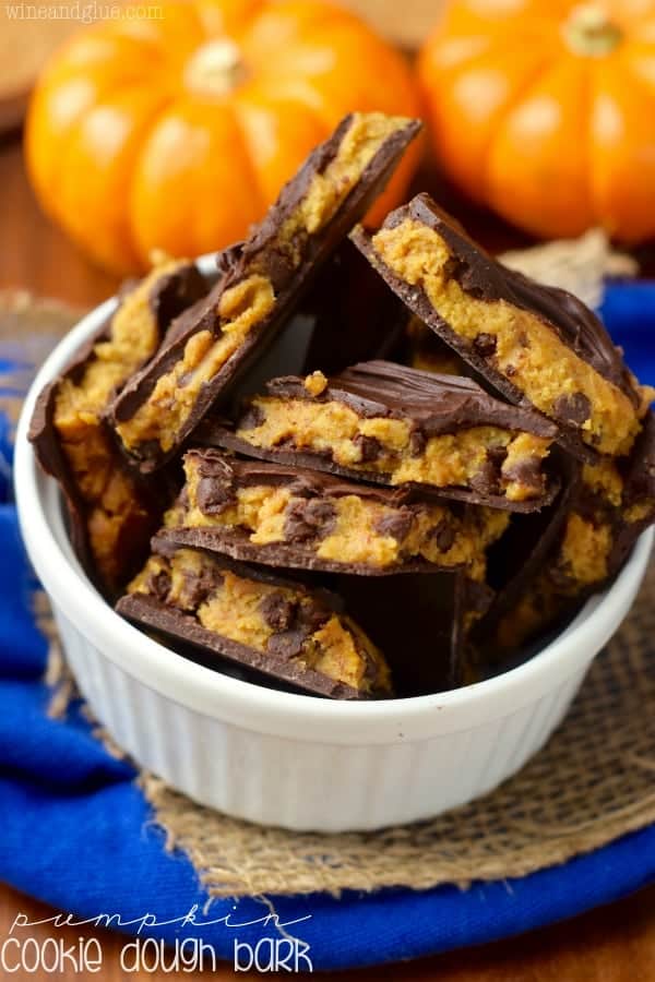 In a ceramic bowl, the Pumpkin Cookie Dough Bark is piled on top of each other showing the pumpkin cookie dough middle. 
