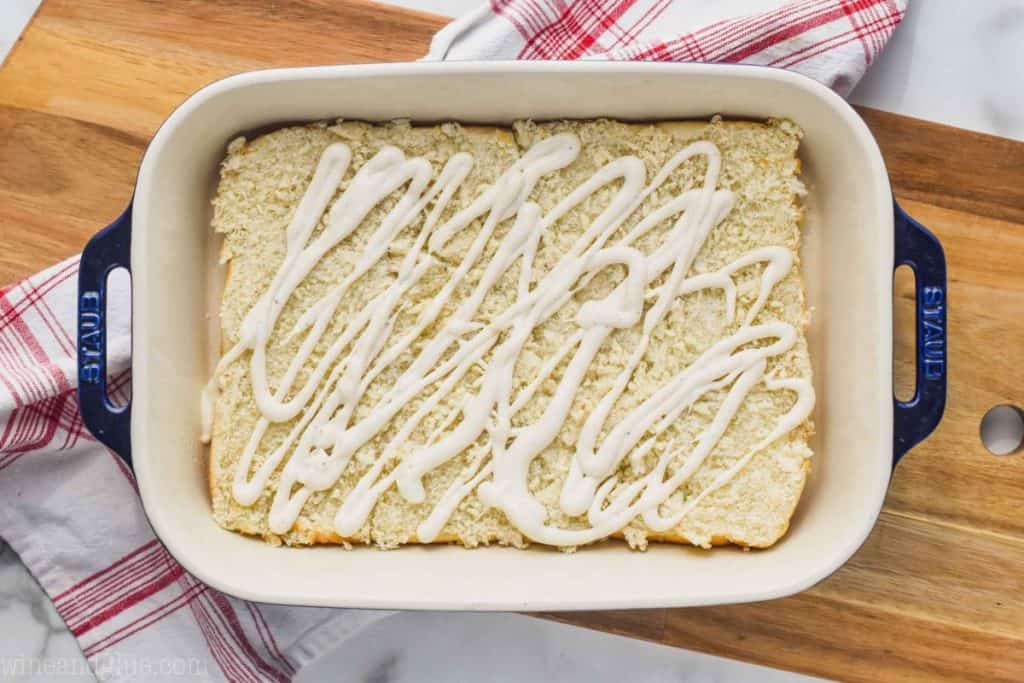 landscape photo of a baking dish on a cutting board with the bottom half of slider rolls and ranch dressing on top