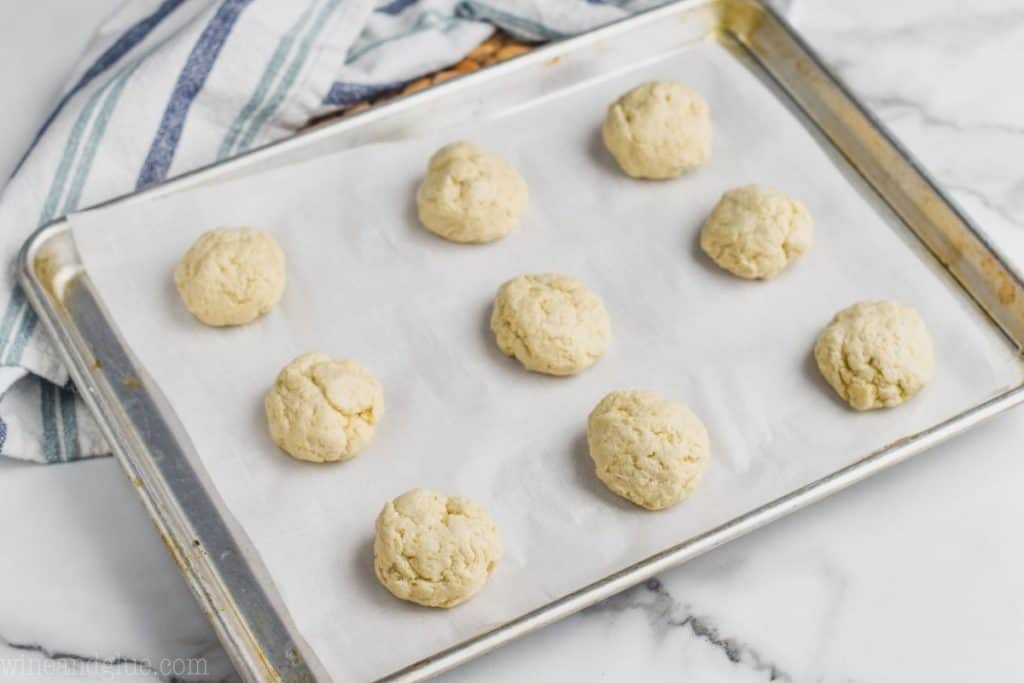 12 raw biscuits on a parchment lined baking sheet