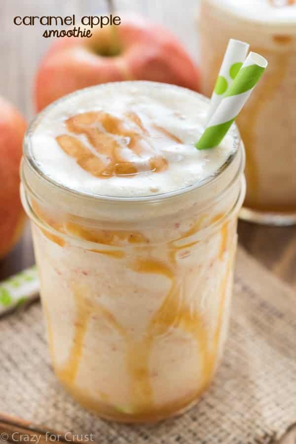 In a mason jar, the Caramel Apple Smoothie has caramel drizzled on the side of the jar with two paper straw. 