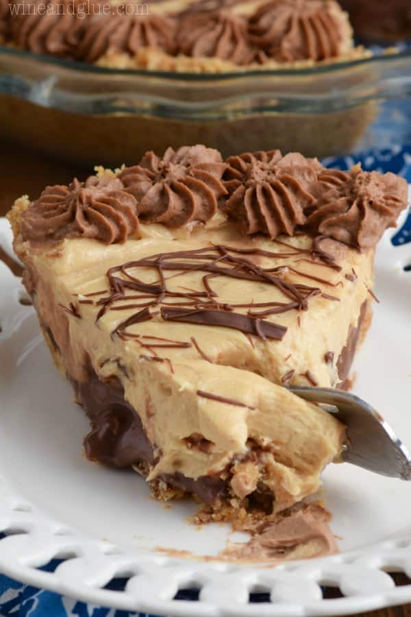 head on picture of a peanut butter cup pie that has been drizzled with chocolate and is being sliced into with a fork