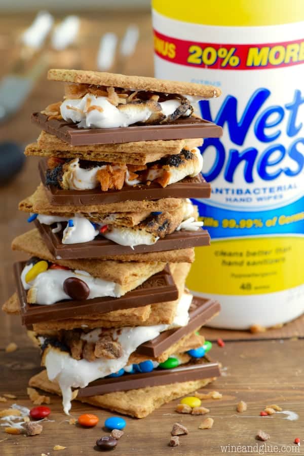 In front of Wet Ones, the Candy Coated S'mores is stacked on top of each other showing the cut chocolate bar, M&Ms, sprinkles, Butterfinger, melted marshmallow, and graham crackers.