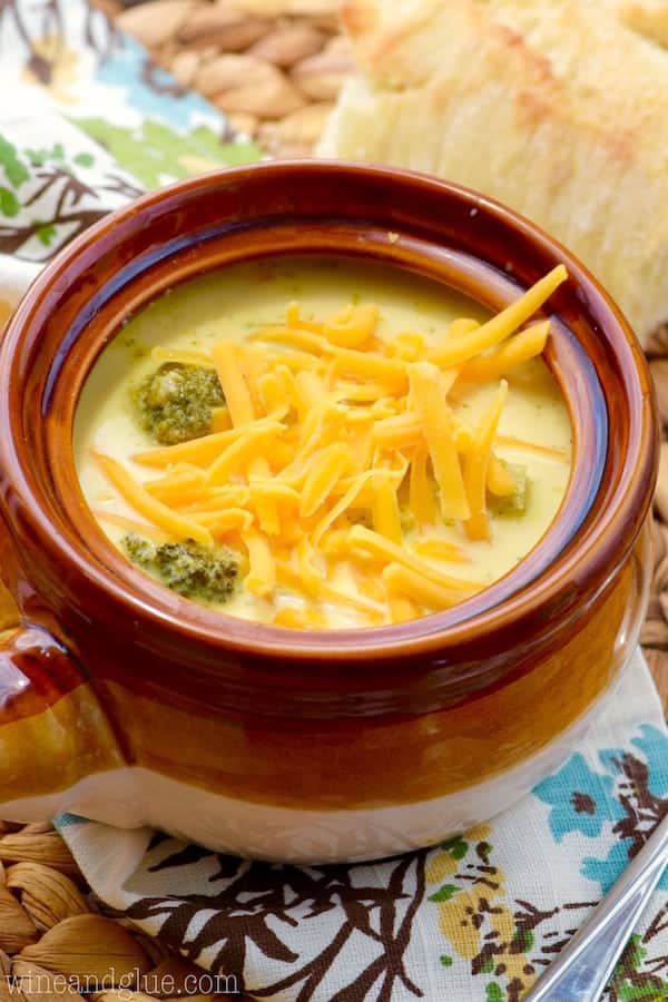 a small soup bowl filled with broccoli cheddar soup topped with shredded cheddar cheese. 