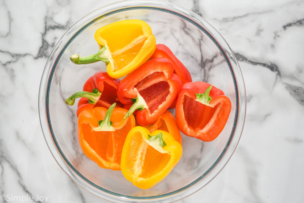 overhead of bell peppers cut in half in a large glass mixing bowl