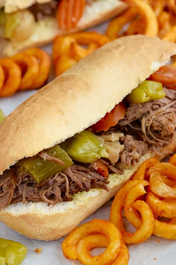 The Crockpot Italian Beef Sandwiches has cooked celery, cut carrots, and sliced pepperoncini which is surrounded by curly fries. 