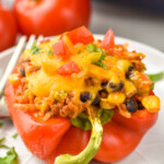 a taco stuffed pepper on a plate topped with chopped tomatoes and cilantro