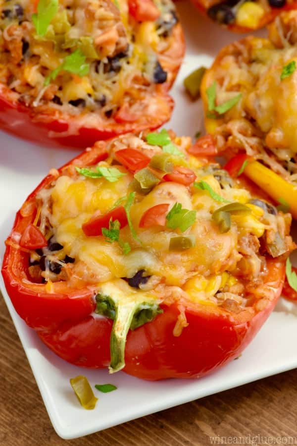 close up of a taco stuffed pepper that has been cut in half and topped with cheese, tomatoes, and jalapeños 