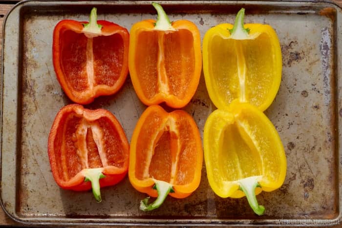3 bell peppers cut in half from top to bottom, de-seeded and sitting on a metal baking sheet