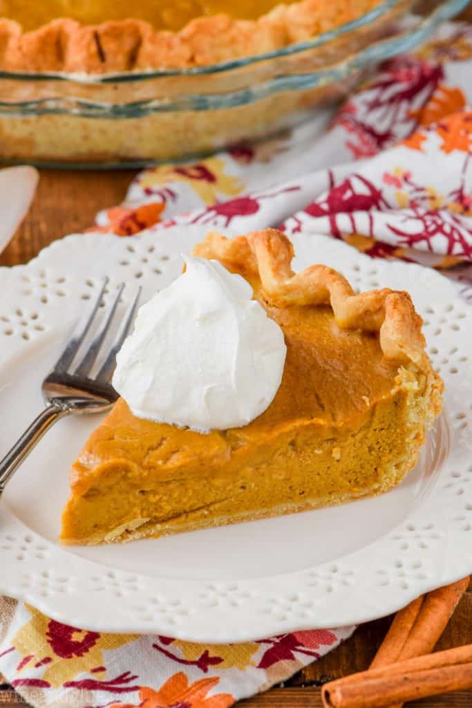 slice of the best pumpkin pie from scratch on a plate with whipped cream
