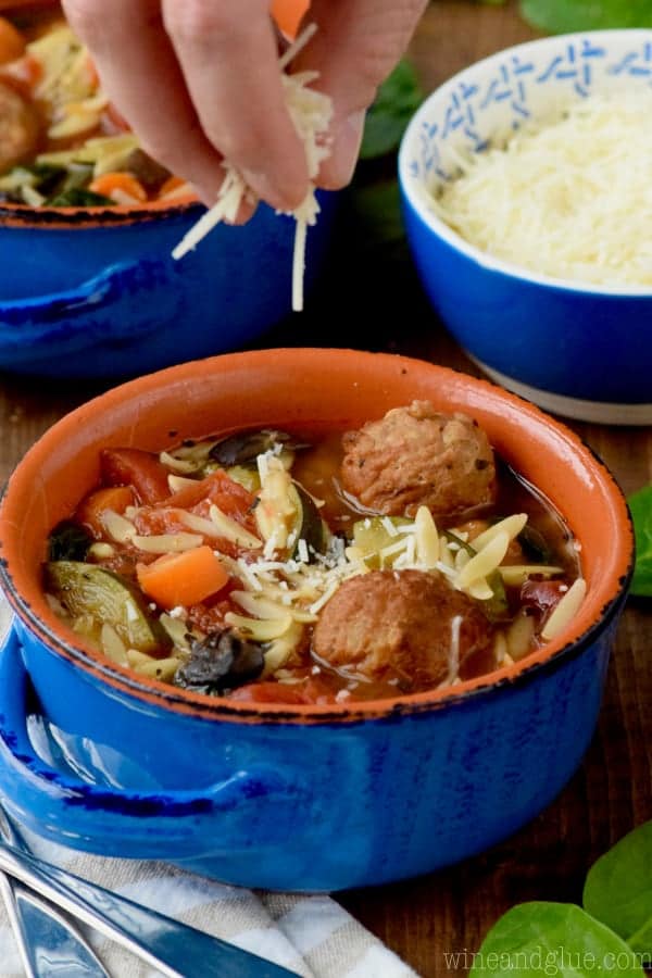 Adding cheese to the bowl of soup. 